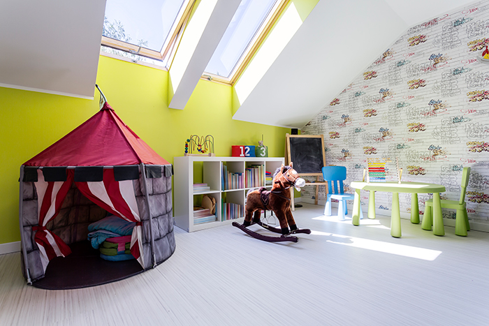 pokój dziecinny ze skośnym oknem na poddaszu pełen kolorowych mebli i zabawek