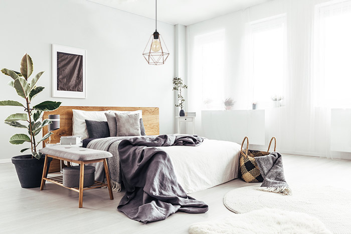Sypialnia w jasnych kolorach w nowoczesnym stylu z lampą wiszącą nad łóżkiem z "otwartym" kloszem i dekoracyjną żarówką