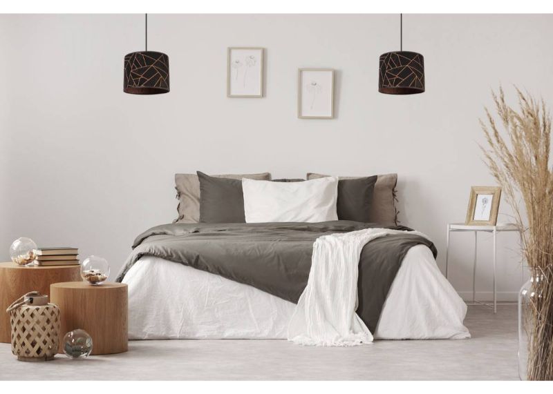 Lampa z abażurem owalnym w kolorze czarnym z geometrycznym wzorem i miedzianym wykończeniem wisząca w sypialni